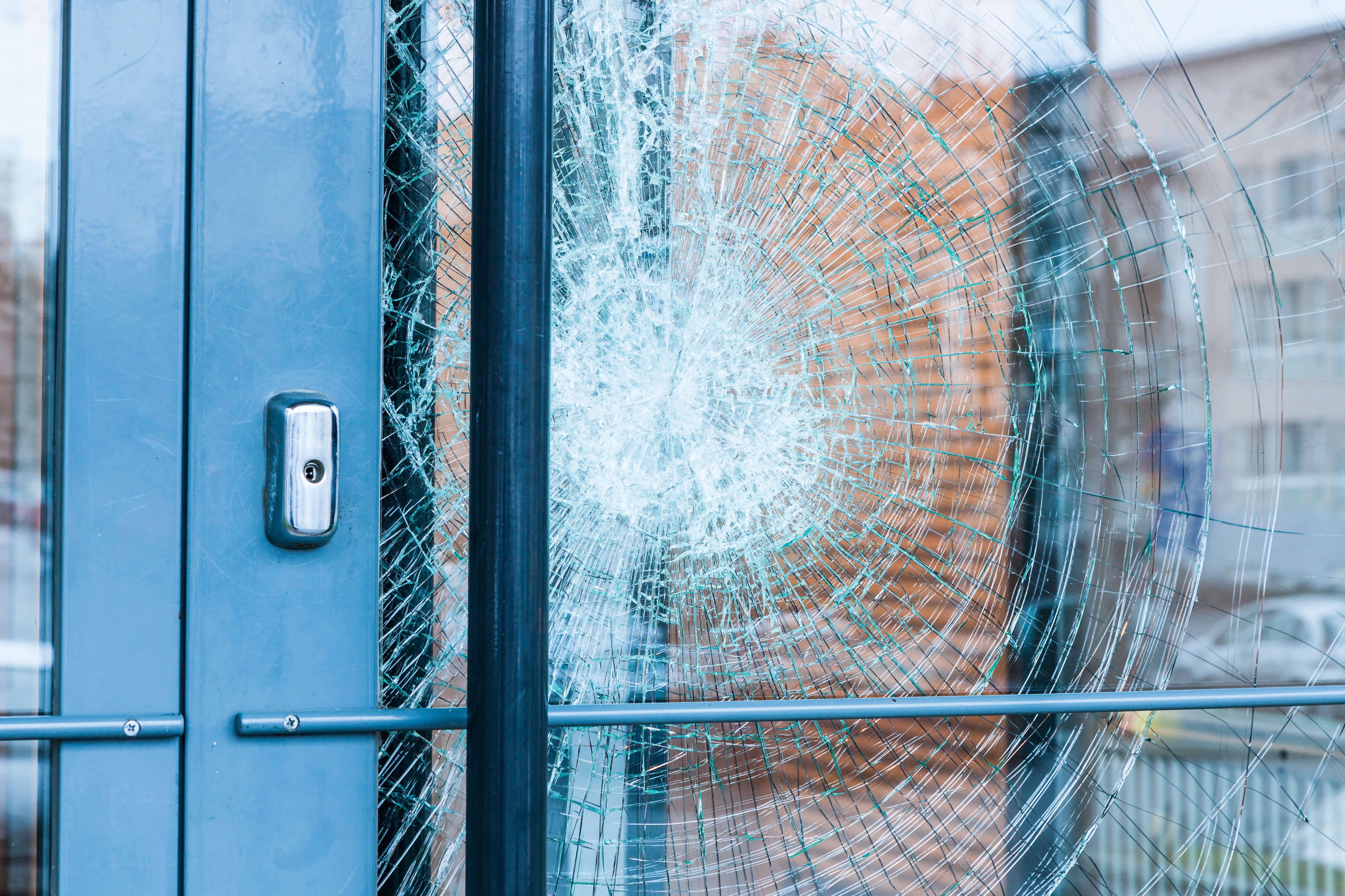 Attempted forced entry on a glass storefront door, pane held in place by security film